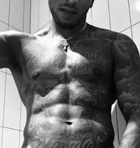 a man with tattoos posing in a bathroom