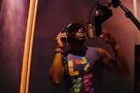 a man in a purple shirt is holding a microphone